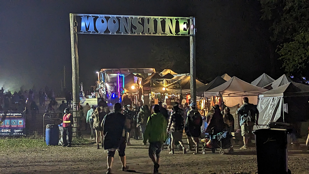 Entrance to the Moonshine stage at Summer Camp indicated by a very tall wooden sign that reads "Moonshine"