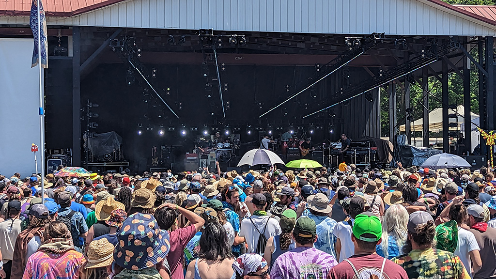 A large music festival crowd in front of a large stage.