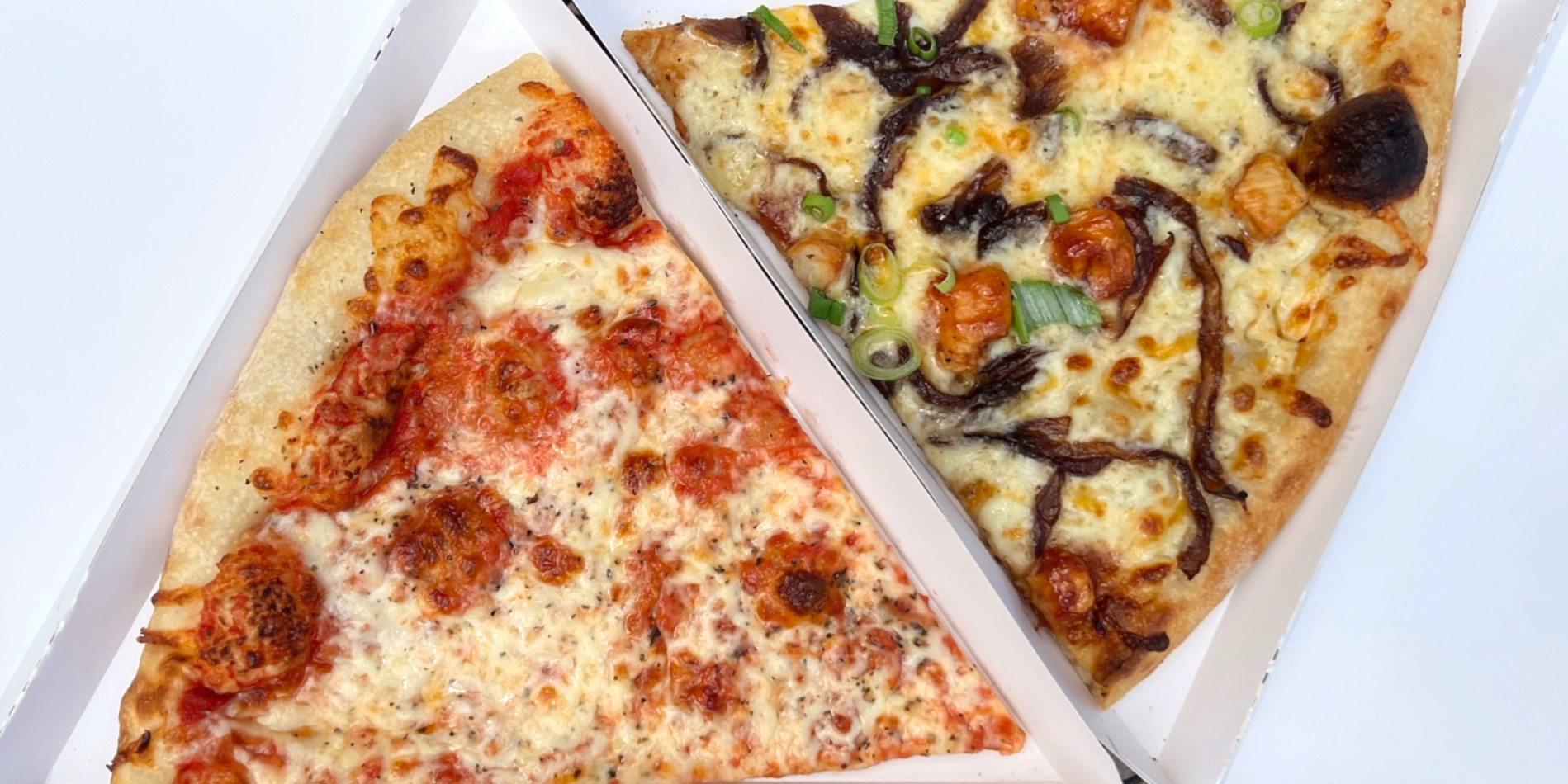 Two slices of pizza from Manolo's Pizza and Empanadas are in white paper pizza boxes for a cheap lunches in Champaign-Urbana list. Cheap lunch in Champaign-Urbana has a slice of cheese and a slice of barbecue chicken ranch for under $10. Photo by Alyssa Buckley.