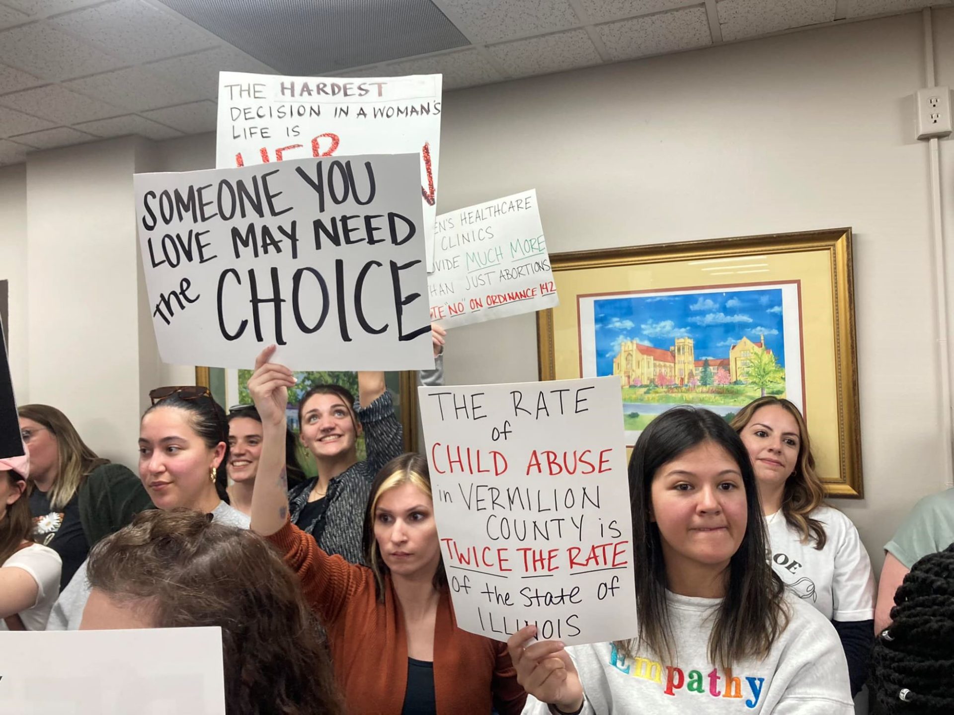 Several women are gathered in a room, holding signs indicating pro-choice views.