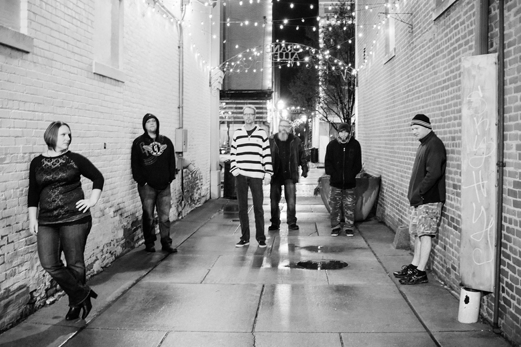 Black and white photo of the six members of Killer Bee Honey in an alley way.