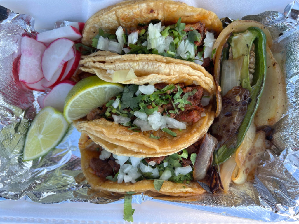 Three tacos from the taco truck Los Hidalguenses. There are raw sliced radish, limes, and grilled onions and pepper. Photo by Alyssa Buckley.