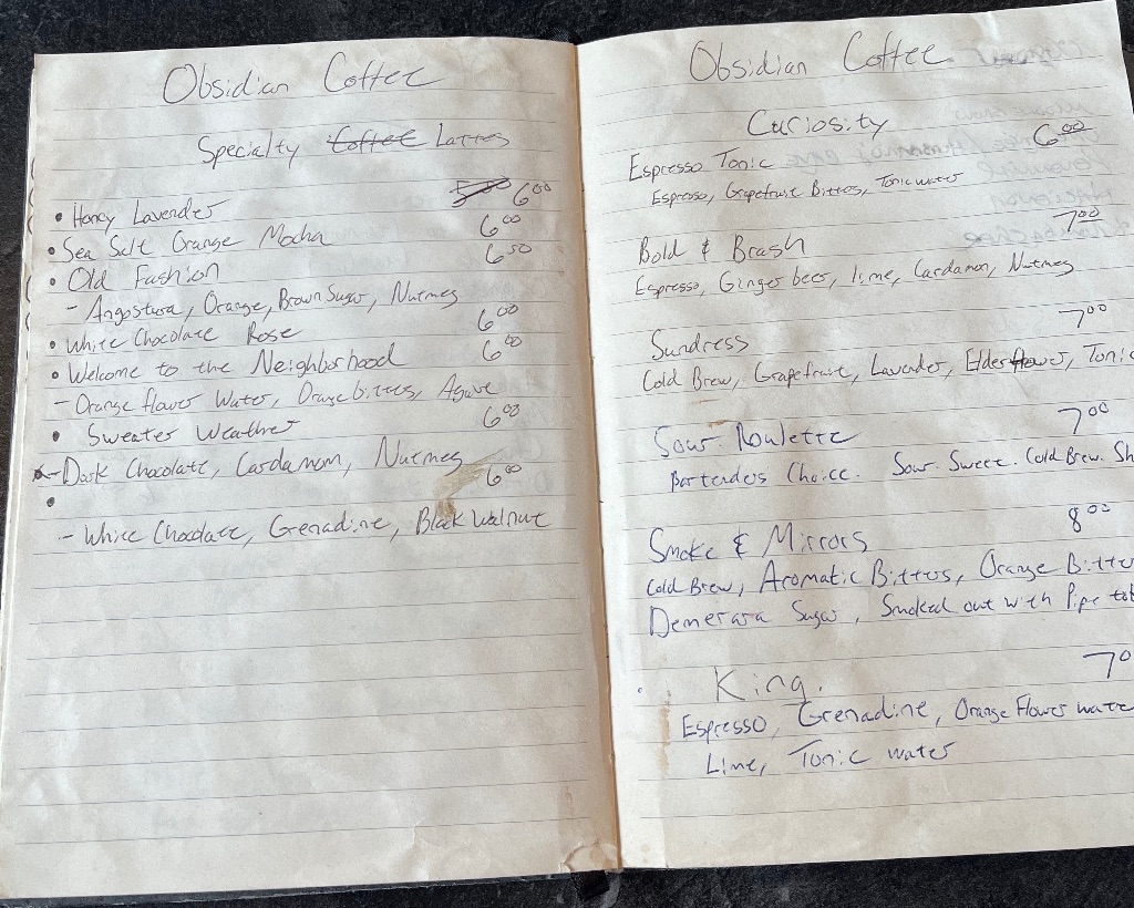 a notebook with small handwriting featuring menu items of various coffee drinks