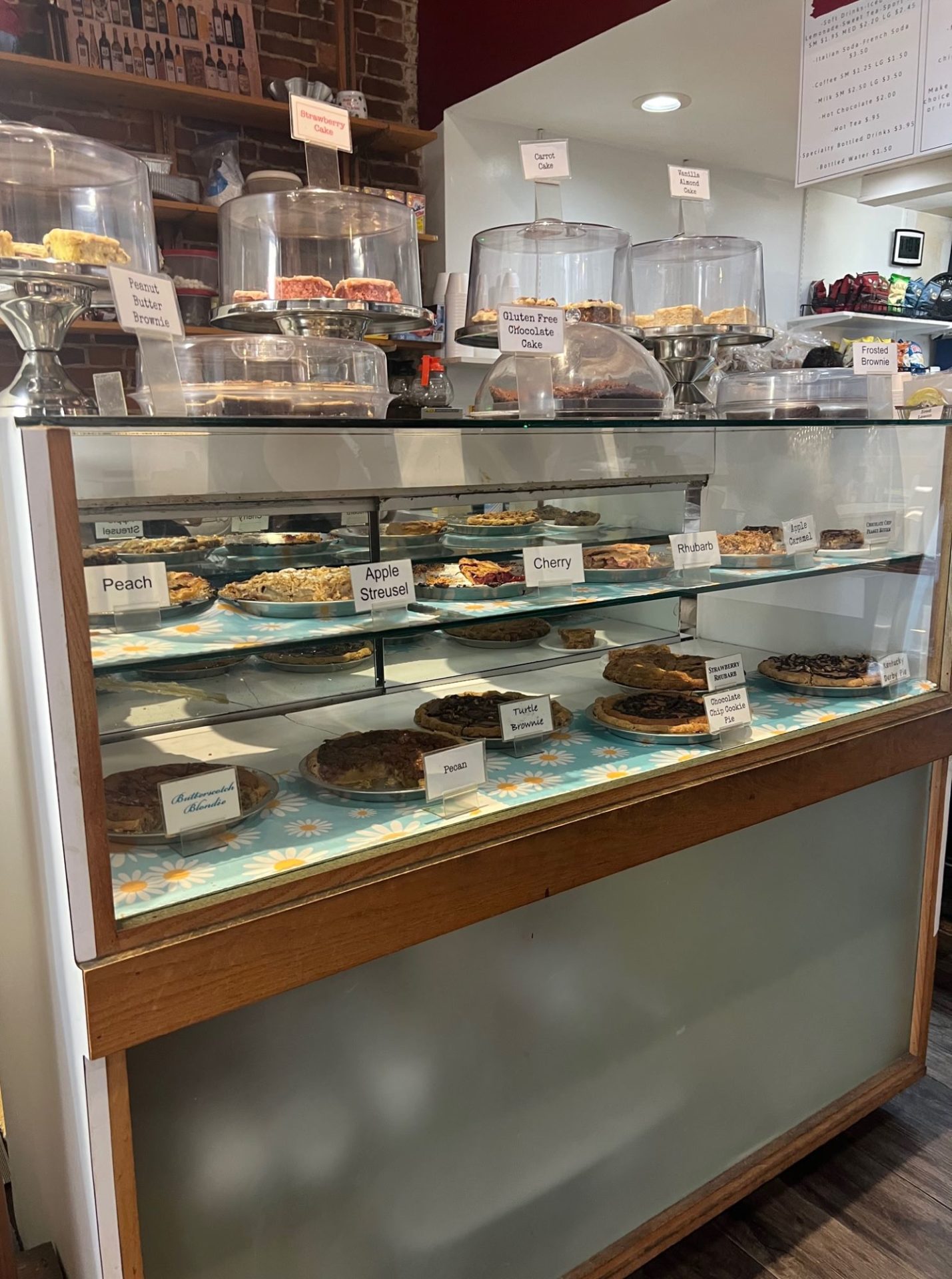 A bakery case with two interior shelves filled with pies. The top of the case has several displays with other desserts encased in them.