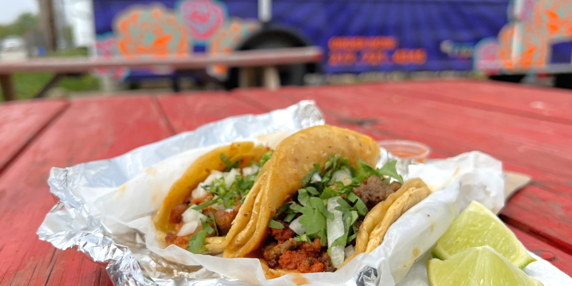 A photo of two tacos on a red table in front of Senores Taco truck. Photo by Alyssa Buckley.