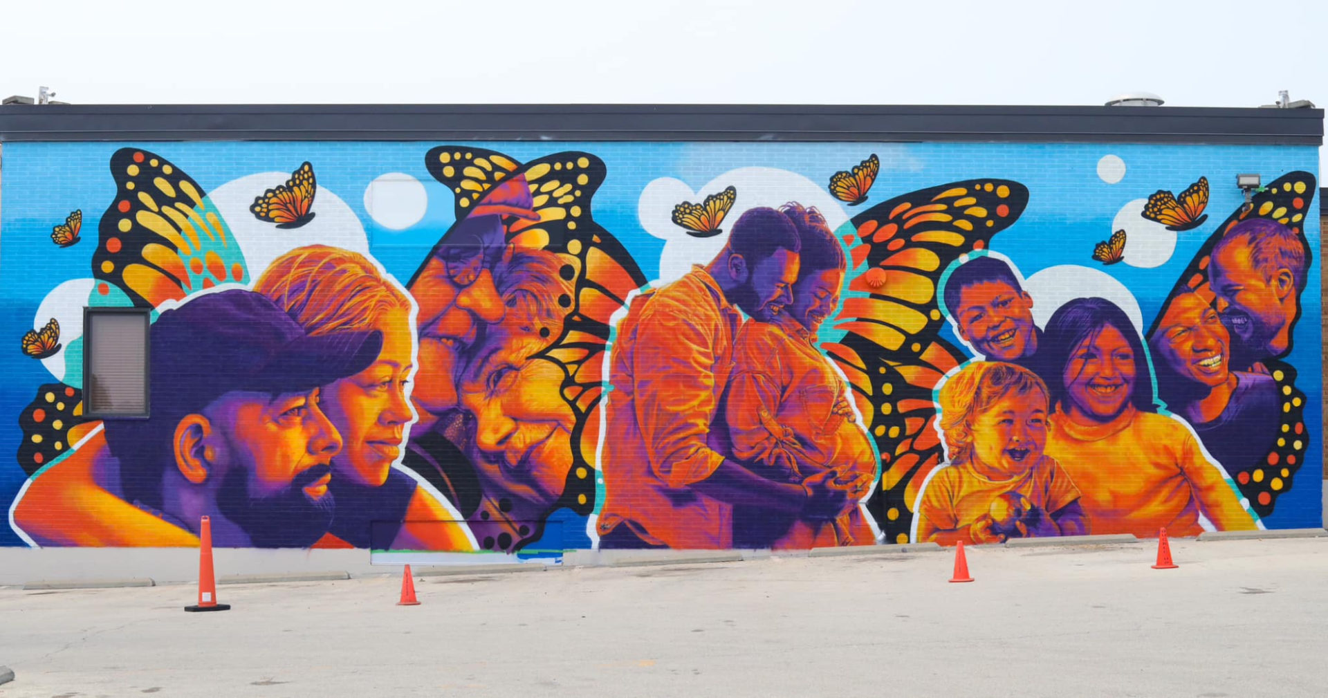 A mural at Champaign Urbana Public Health District by Jose Vazquez. It features 11 different people, all painted among and the colors of monarch butterflies.