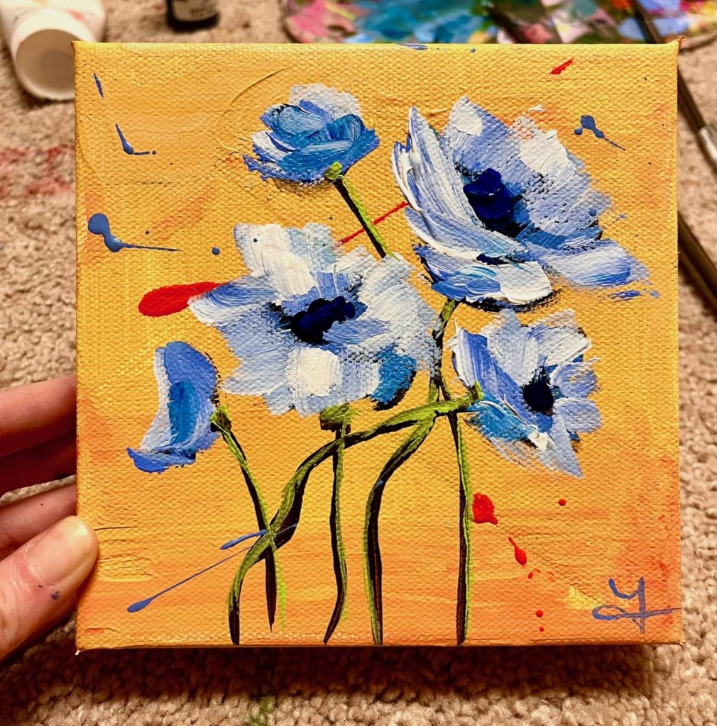 a small yellow square canvas with blue flowers