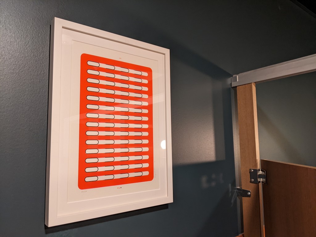 a navy blue wall with an orange print framed in a white frame