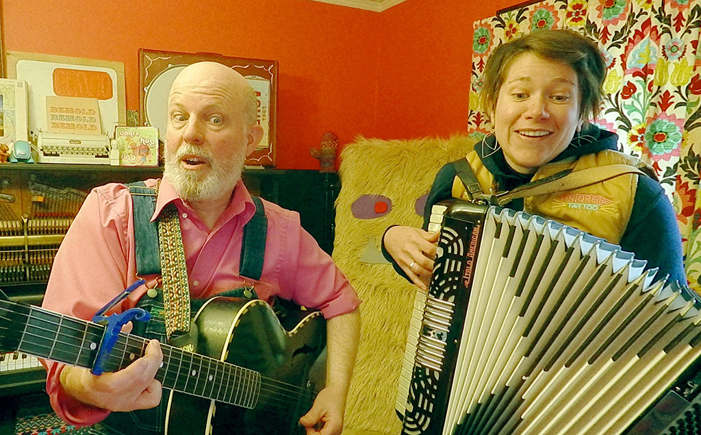 A man playing guitar on the left with a woman playing an accordion on the right