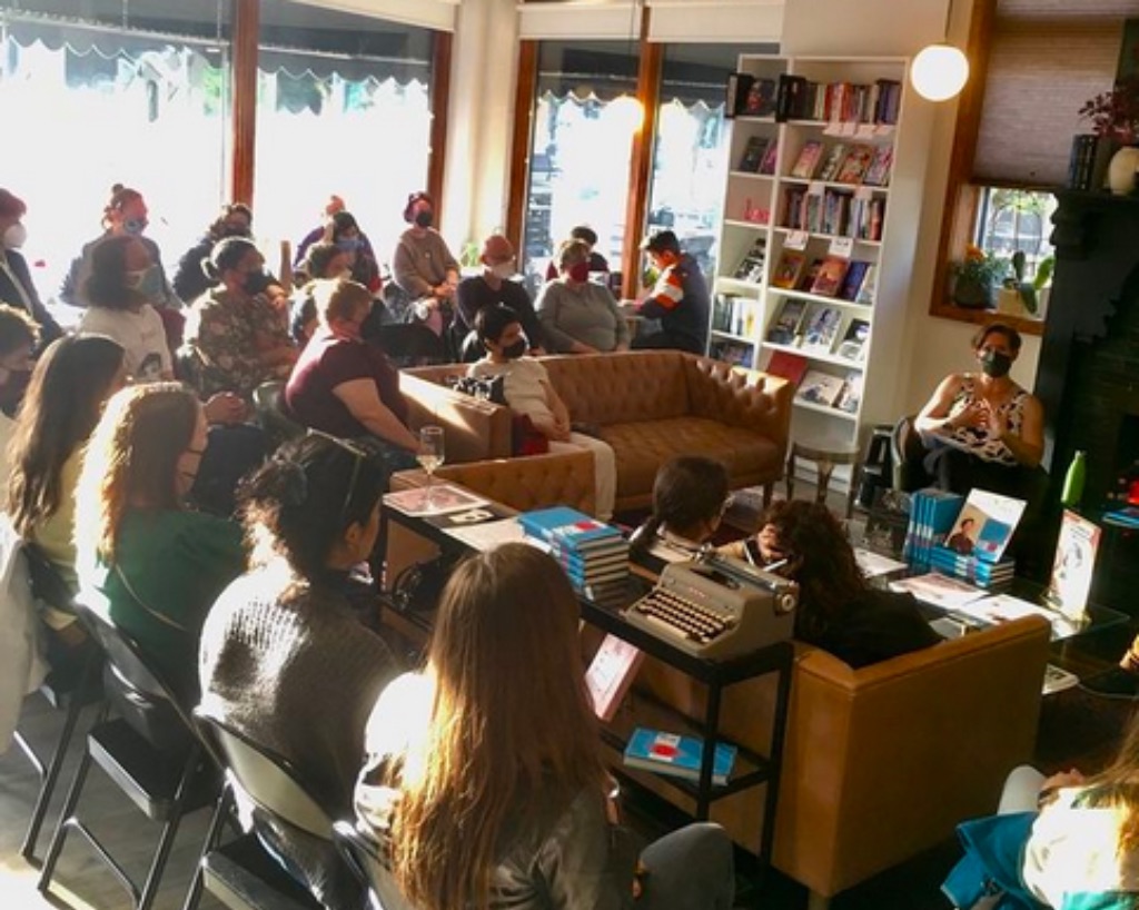 A group gathers in a bookstore sitting on couches and chairs seated in a semi-circle