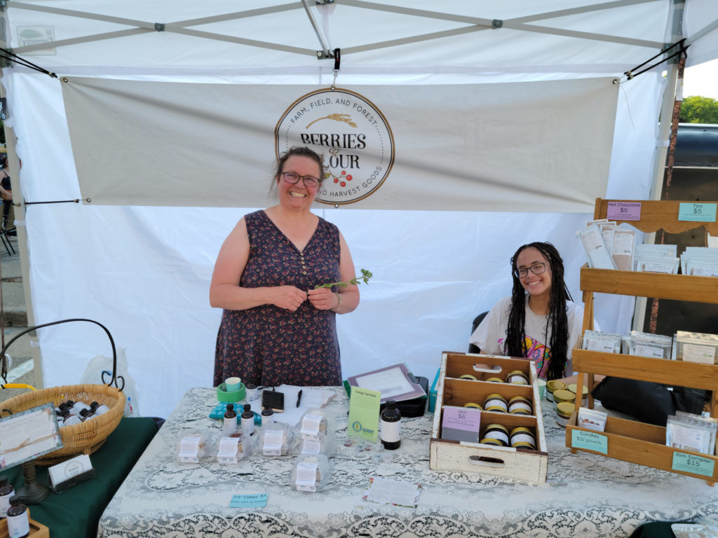 Berries & Flour owner Heidi Leuszler and one of her staff smiling behind their booth at the Champaign Farmer’s Market. Photo by Matthew Macomber.
