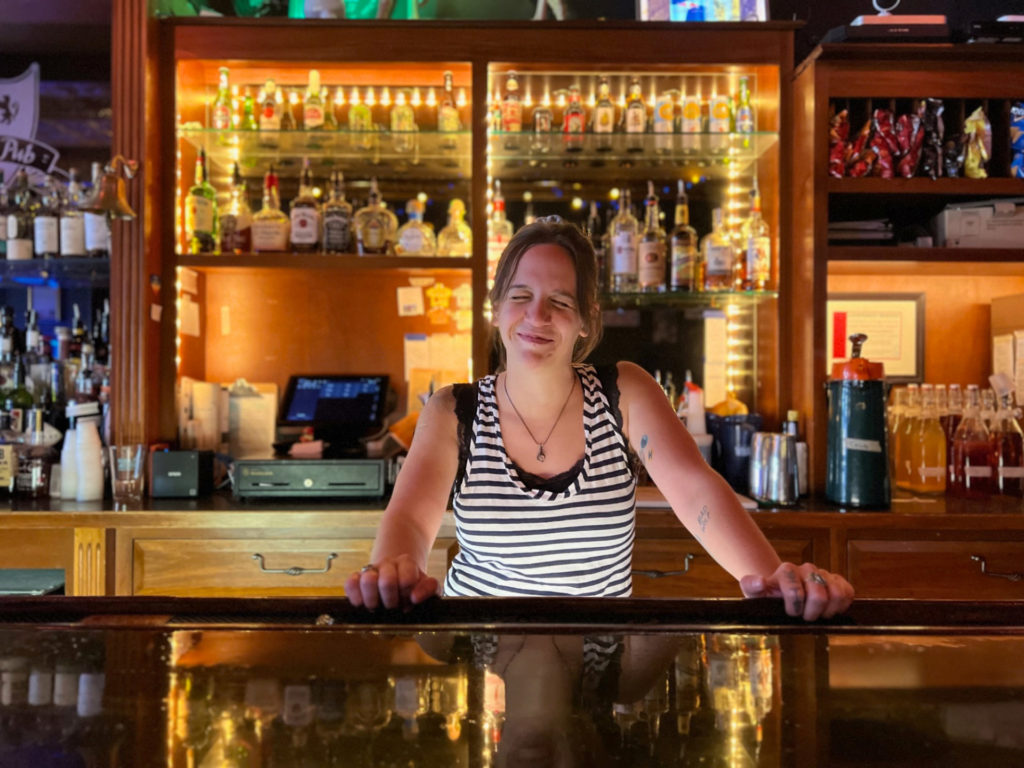 Katie Carrillo is behind the bar at Bentley's Pub, and her eyes are closed with a smile. Photo by Alyssa Buckley.