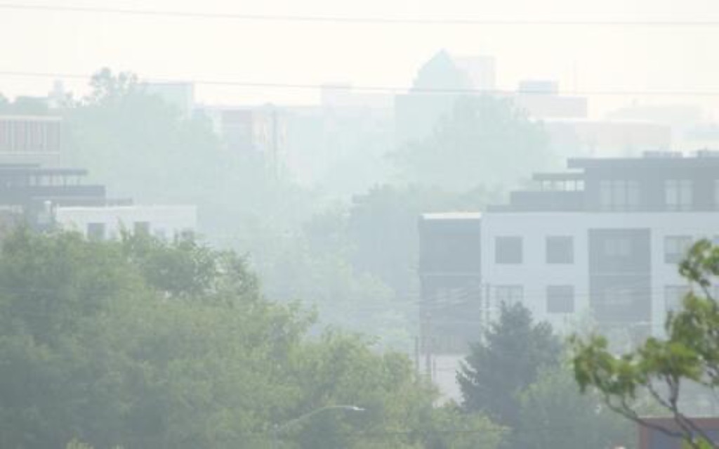 A panoramic image of buildings in Champaign, IL. There is a smoky haze covering the whole sky in a gray smoke. 