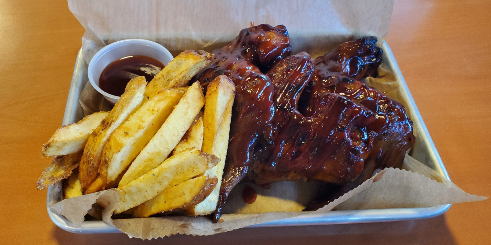 A cropped image of wings and fries from Sooie Bros Bar-B-Que Joint. Photo by Carl Busch.