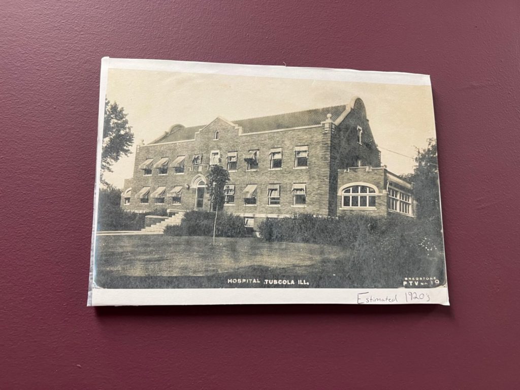 A sepia toned photo of a brick building with the words Hospital, Tuscola, ILL. in white lettering.