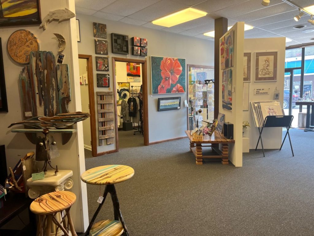 An inside look at the Vault Art Gallery. An open space filled with art on the walls, and dividers in the room with more art 
