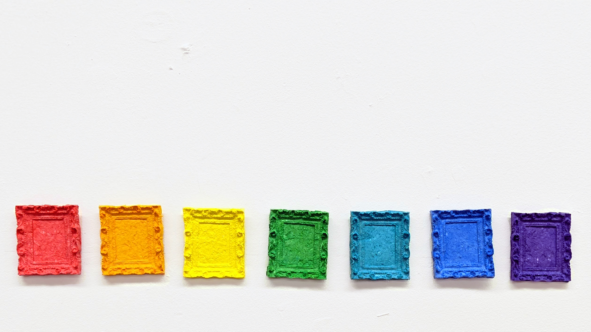 Small blocks of colorful embossed paper against a white backdrop. The paper is in rainbow order: red, orange, yellow, green, blue, indigo, violet