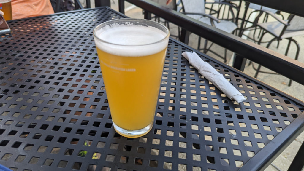 A pint glass of summer shandy sits on a black outdoor table at Three Ravens in Monticello. Photo by Taylor Judd.