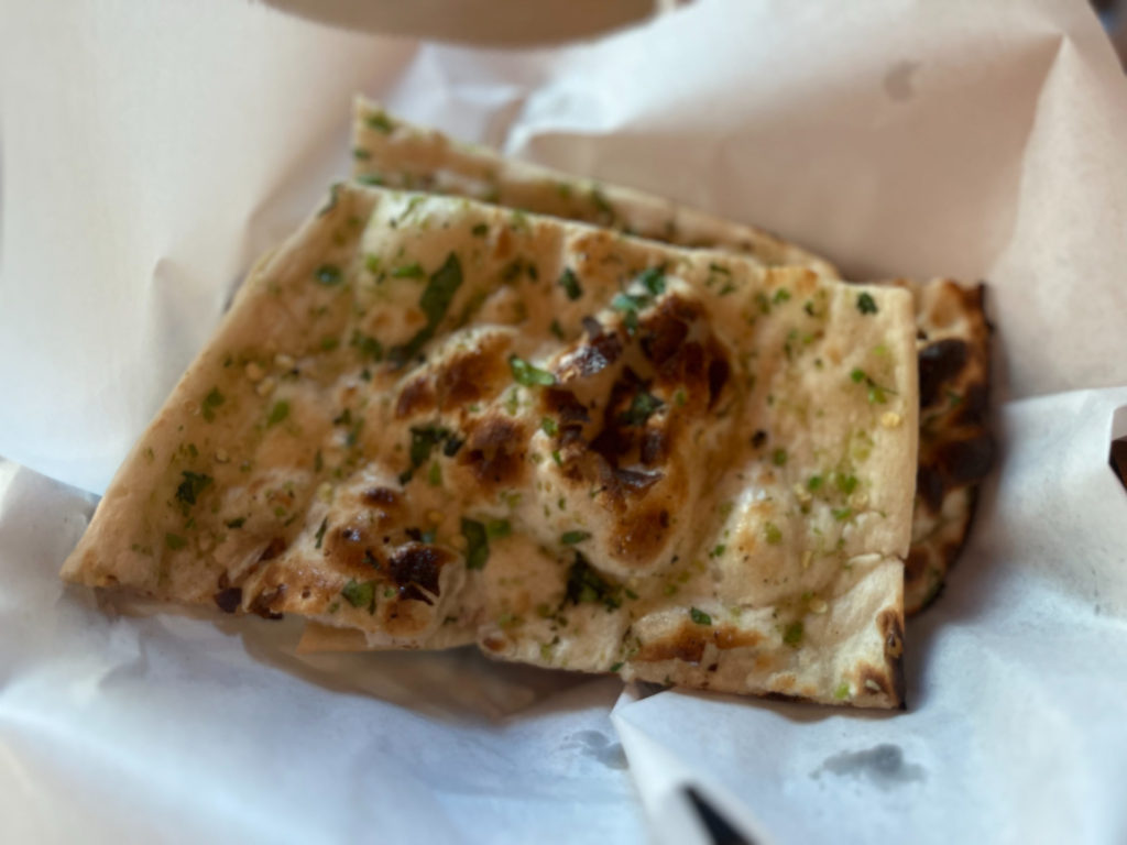 In a basket lined with white parchment paper, there is garlic chili naan from NAYA. Photo by Ayesha Mehta.