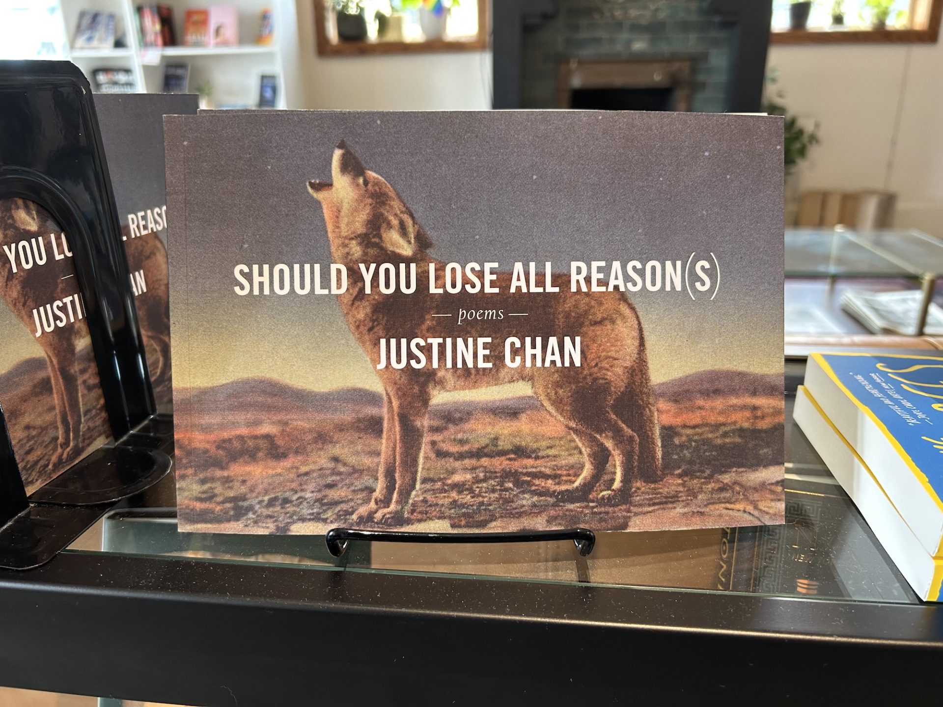 Cover of Should you lose all reason(s) by Justin Chan. It is on display at the literary. the backround of the book is a howling wolf.