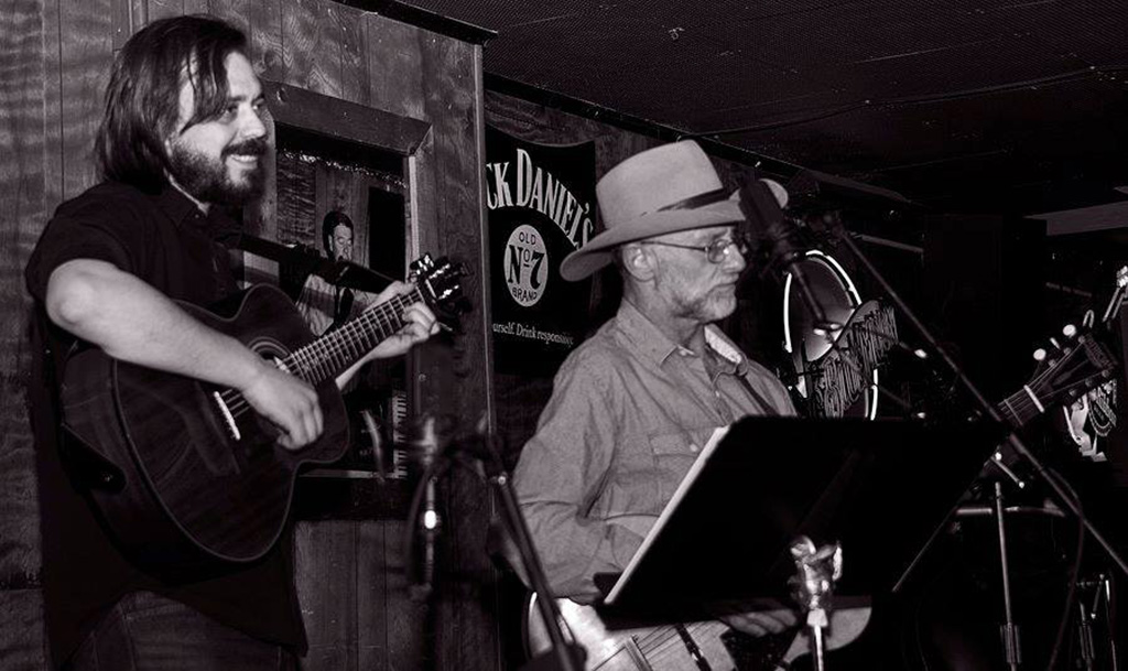 Black and white photo of two men performing onstage