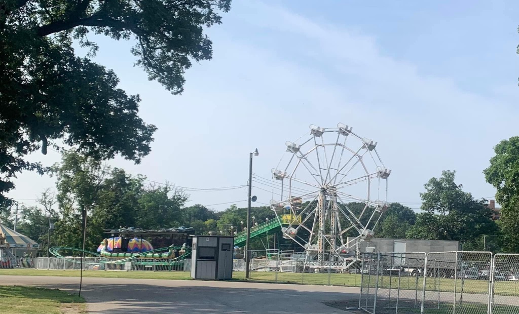 A picture of the county fair. You can see a Farris wheel and other rides. 
