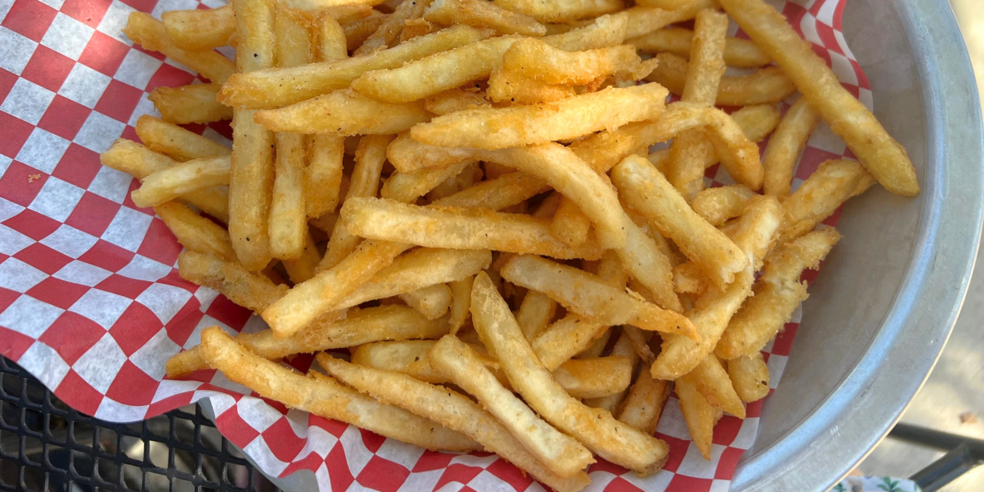 A cropped image of French fries in Champaign-Urbana on a red-and-white checkered parchment paper at Farren's Pub. Photo by Alyssa Buckley.