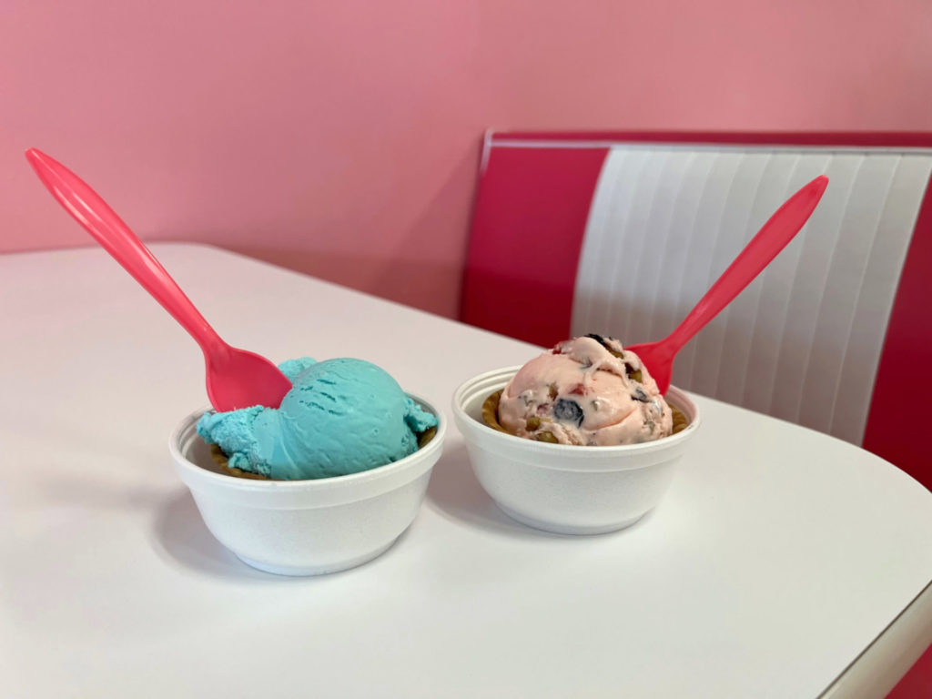 Two delicious ice cream cups from La Michoacana Express in Urbana, Illinois sit on a white table in front of a pink and white booth. Photo by Alyssa Buckley.