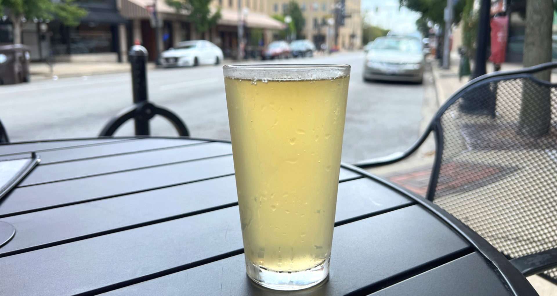 On a black patio table in Champaign outside of Farren's Pub, there is a draft pour of the lemon balm ginger kombucha by Cloud Mountain Kombucha. Photo by Alyssa Buckley.