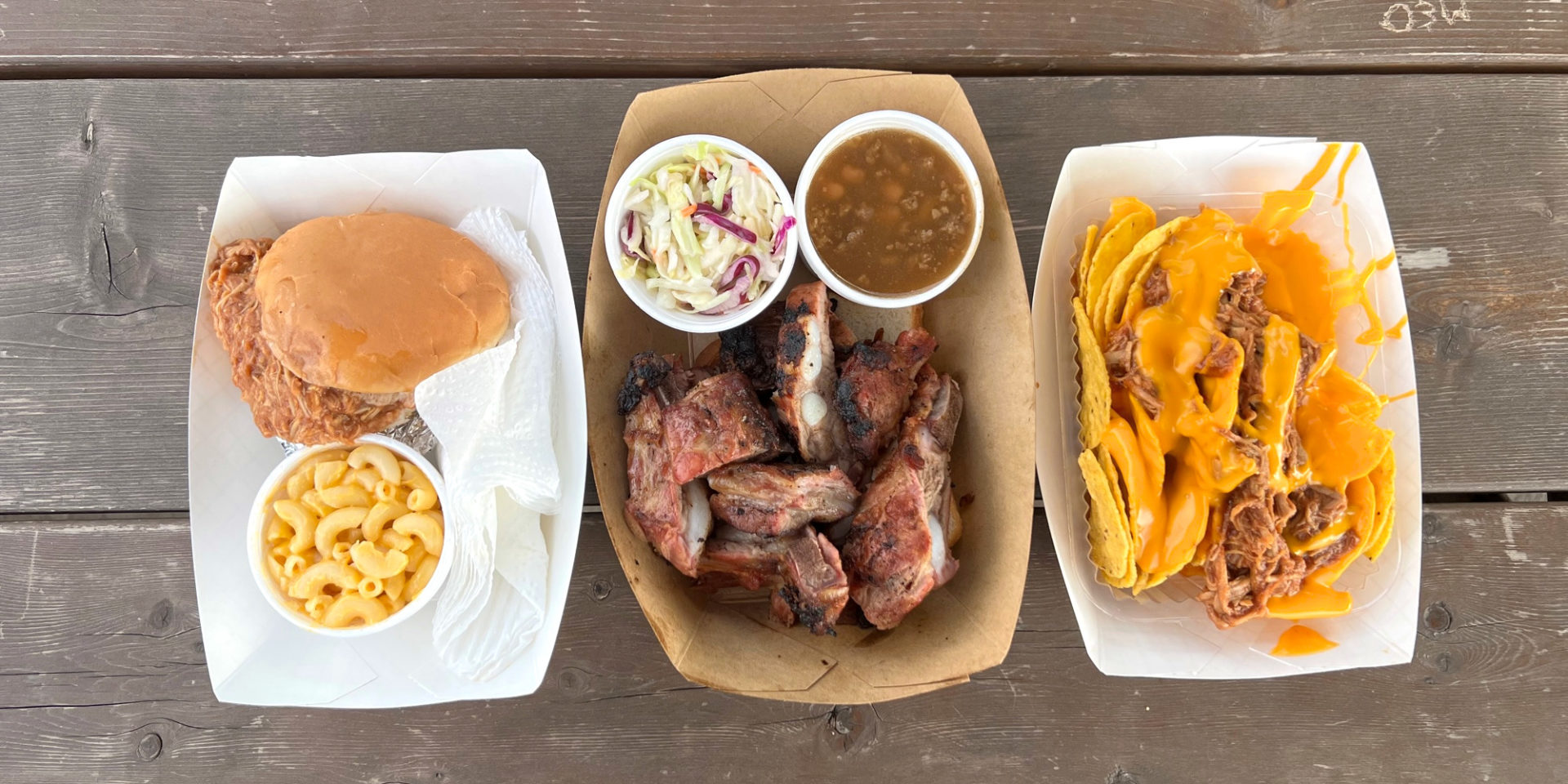 An overhead photo of food from Mama Duke's food truck: a chicken sandwich with macaroni, rib tips and two sides, and nachos. Photo by Alyssa Buckley.