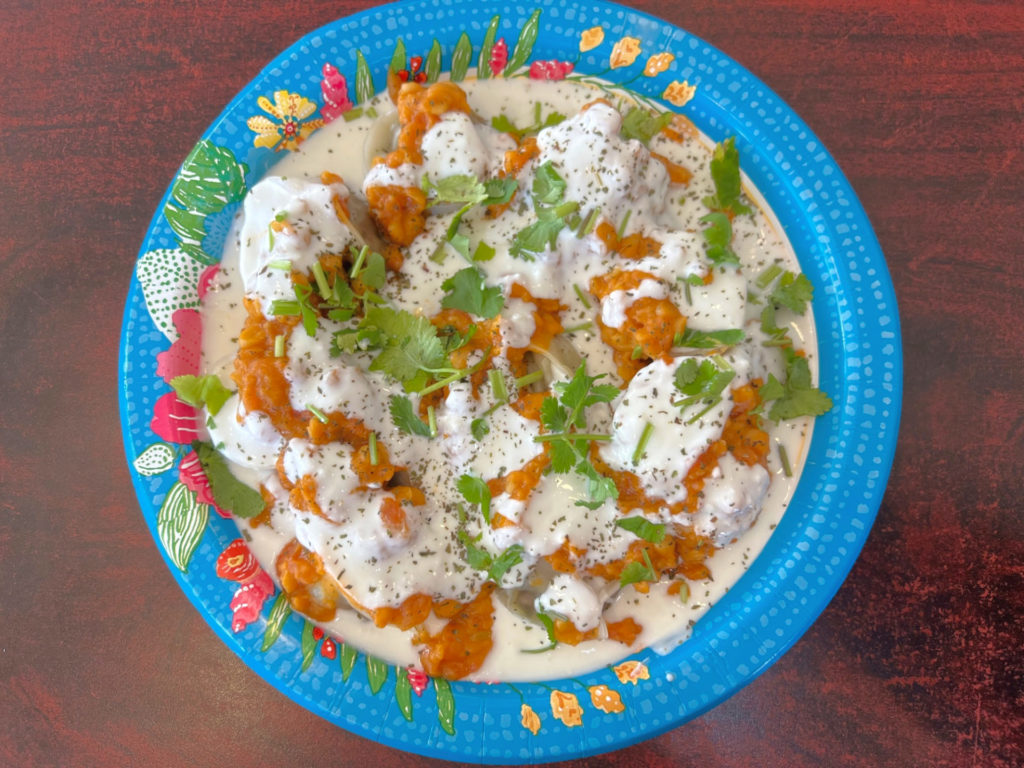 A plate of mantu, or Afghani dumplings, from the Afghan Cuisine restaurant. The dumplings have a white garlic yogurt sauce and an orange lentil sauce with lots of fresh cilantro on top. Photo by Alyssa Buckley.