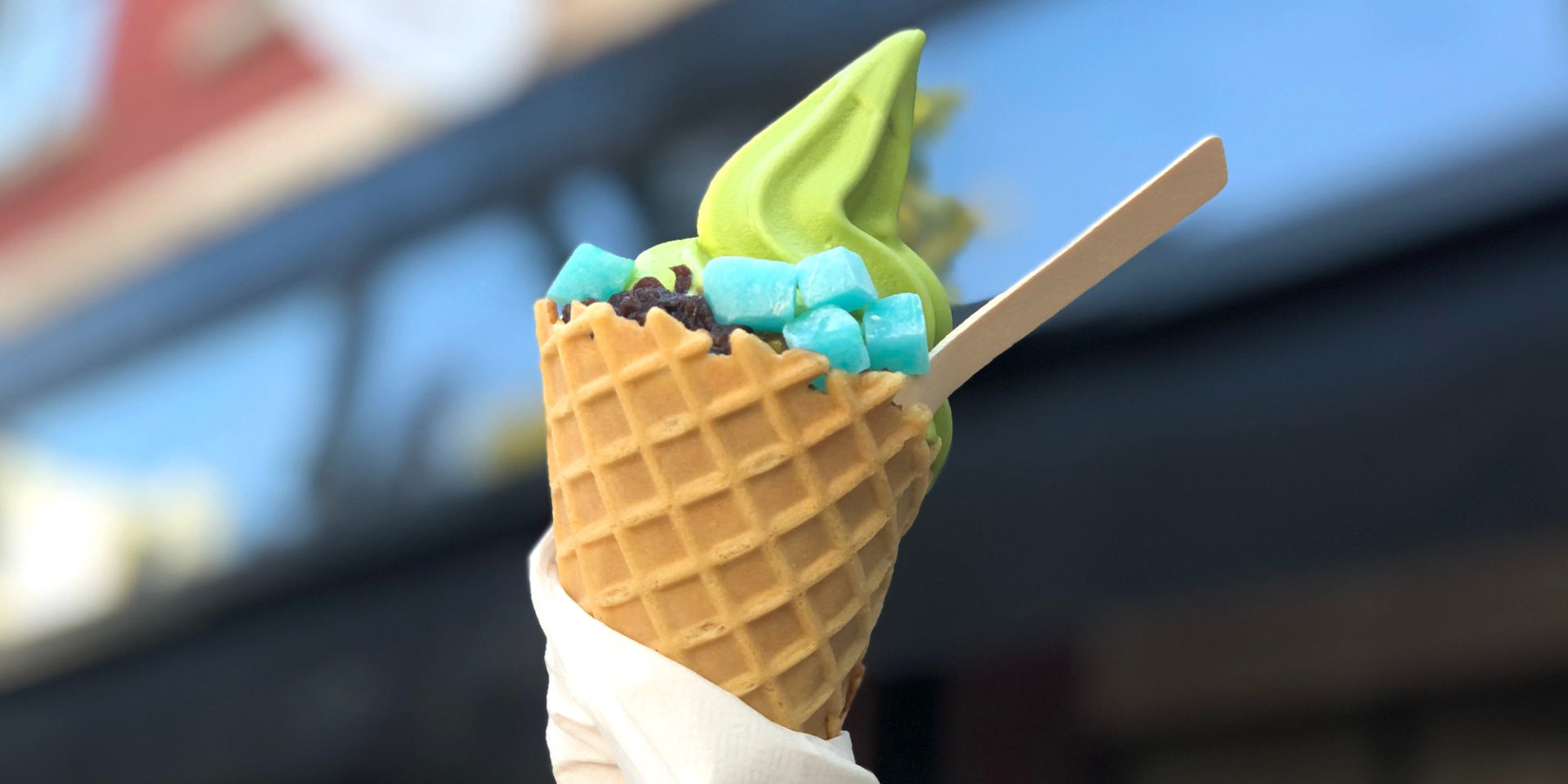 The header image for National Ice Cream Day and National Ice Cream Month in Champaign-Urbana. It is a cone with green matcha ice cream and housemade Japanese sweet toppings with a wooden spoon sticking out the right side. Photo by Alyssa Buckley.