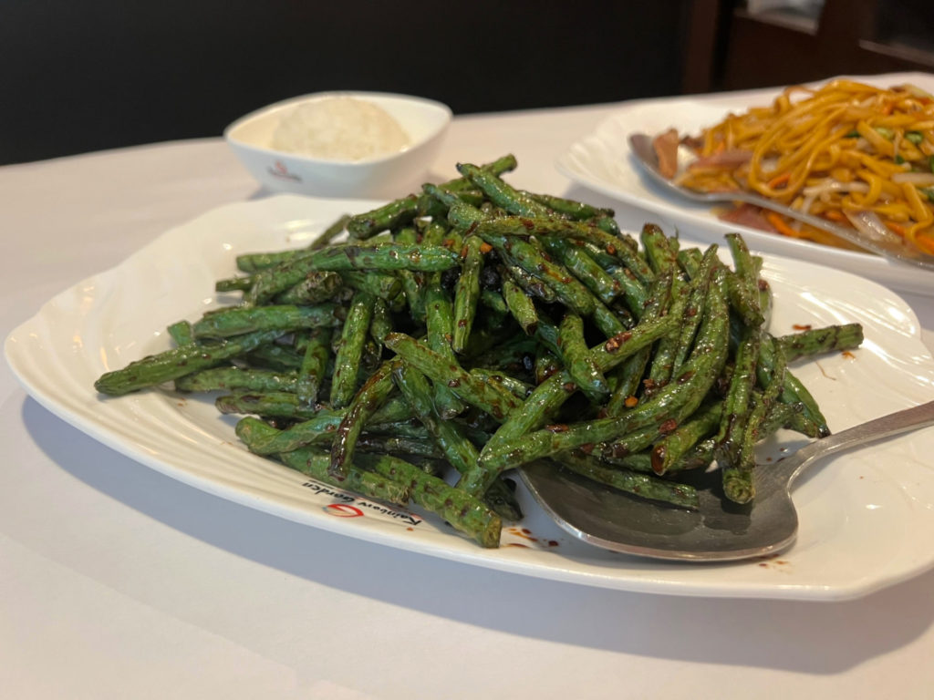 A white plate holds green beans with a black bean sauce at Rainbow Garden Chinese restaurant. Photo by Alyssa Buckley.