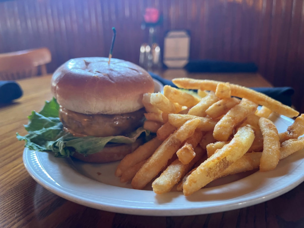 At Silvercreek, there is a white plate with a burger and side of fries in Champaign-Urbana. Photo by Alyssa Buckley.