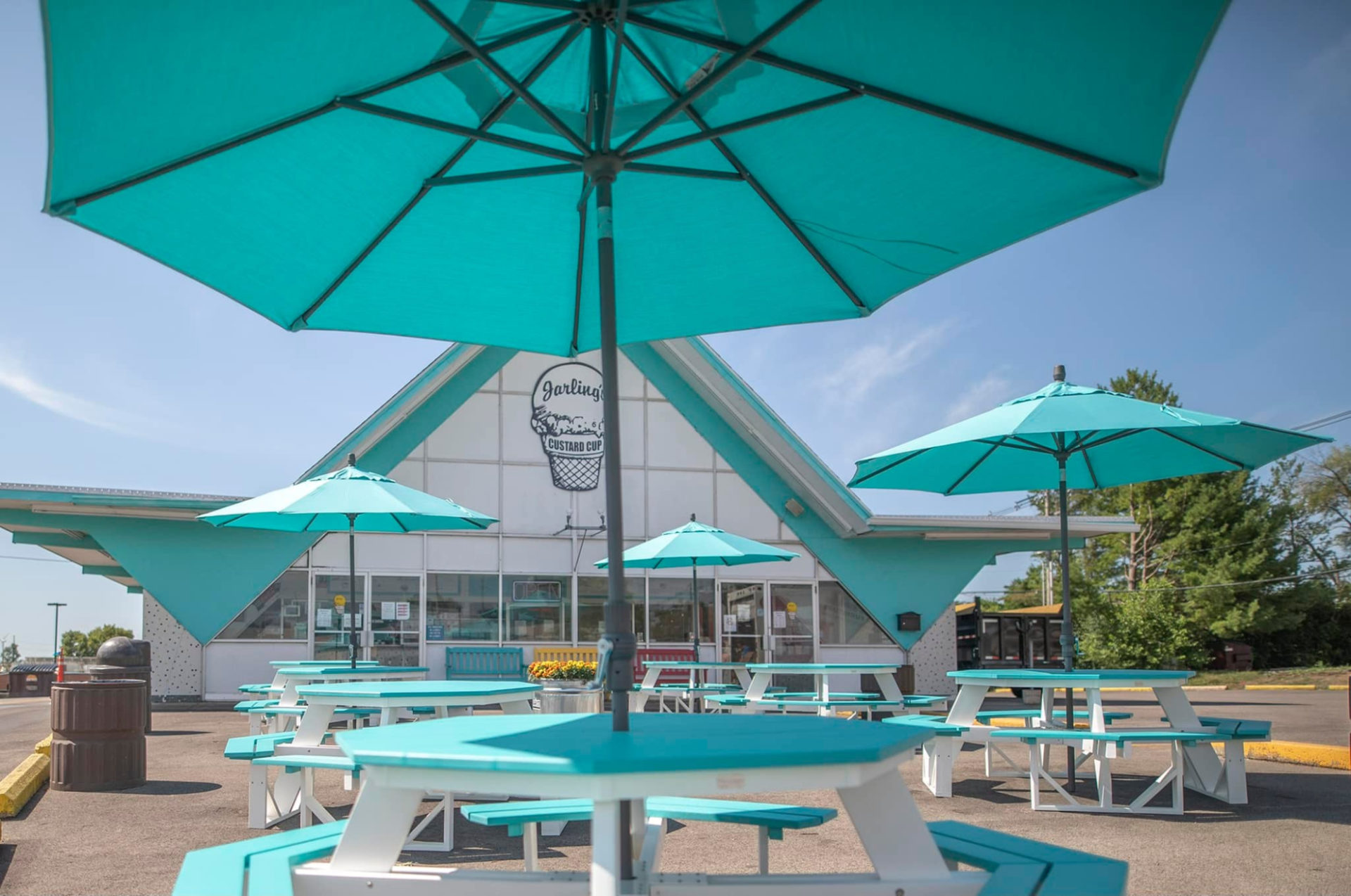 New seating at Jarling's Custard Cup. Light teal round picnic tables with matching umbrellas are seen in front of the building.