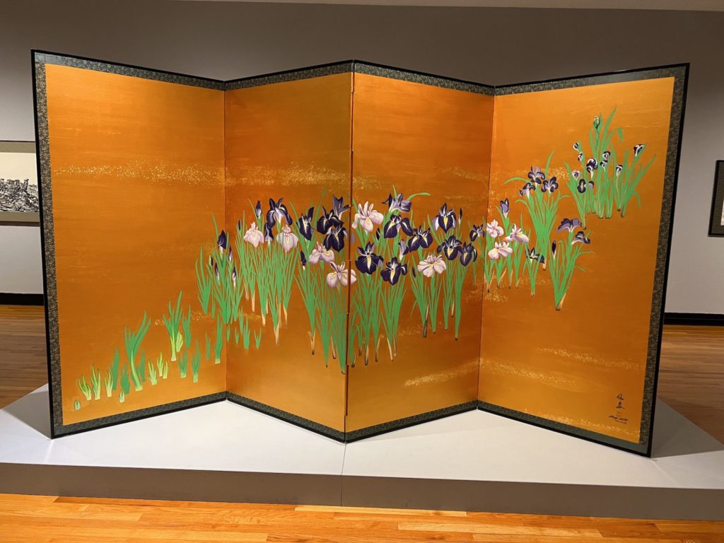 a large 4 panel screen in orange with green stems and flowers taking up approximately 1/3 of the surface, starting in the bottom left and progressing to the top right of the screen