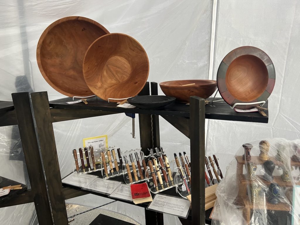 Wooden plates stand on a bookshelf in an outdoor tent