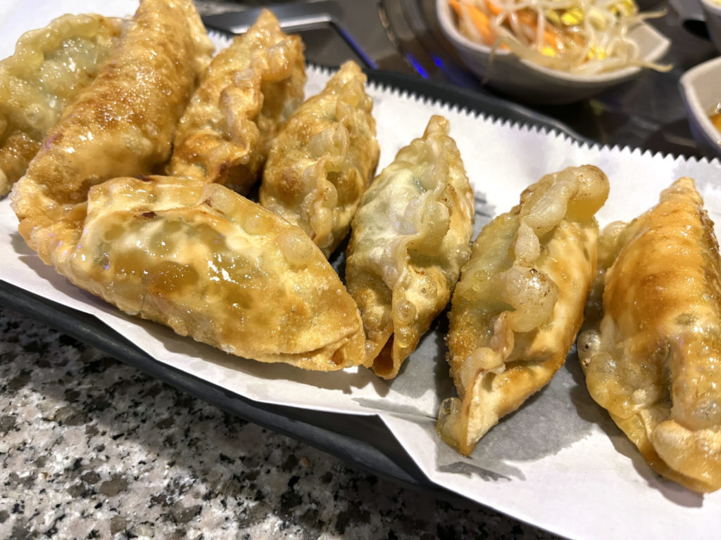 Fried pork dumplings at Star BBQ. Eight fried, golden brown dumplings in on a plate covered in white paper to absorb oil.