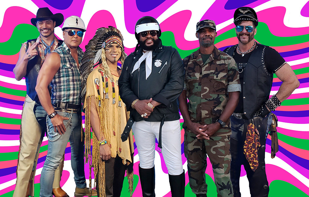 This is a photo of a group of people standing in front of a colorful psychedelic background. The people are dressed in various styles, including casual, military, and punk. The background is a mix of pink, green, and purple swirls and patterns.