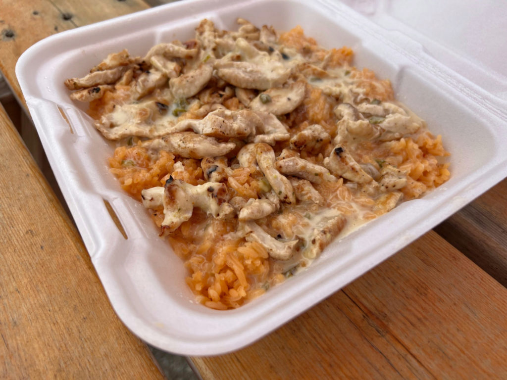 In a takeout container, there is chopped chicken with queso on top of Mexican rice from Los Paisas food truck. Photo by Alyssa Buckley.