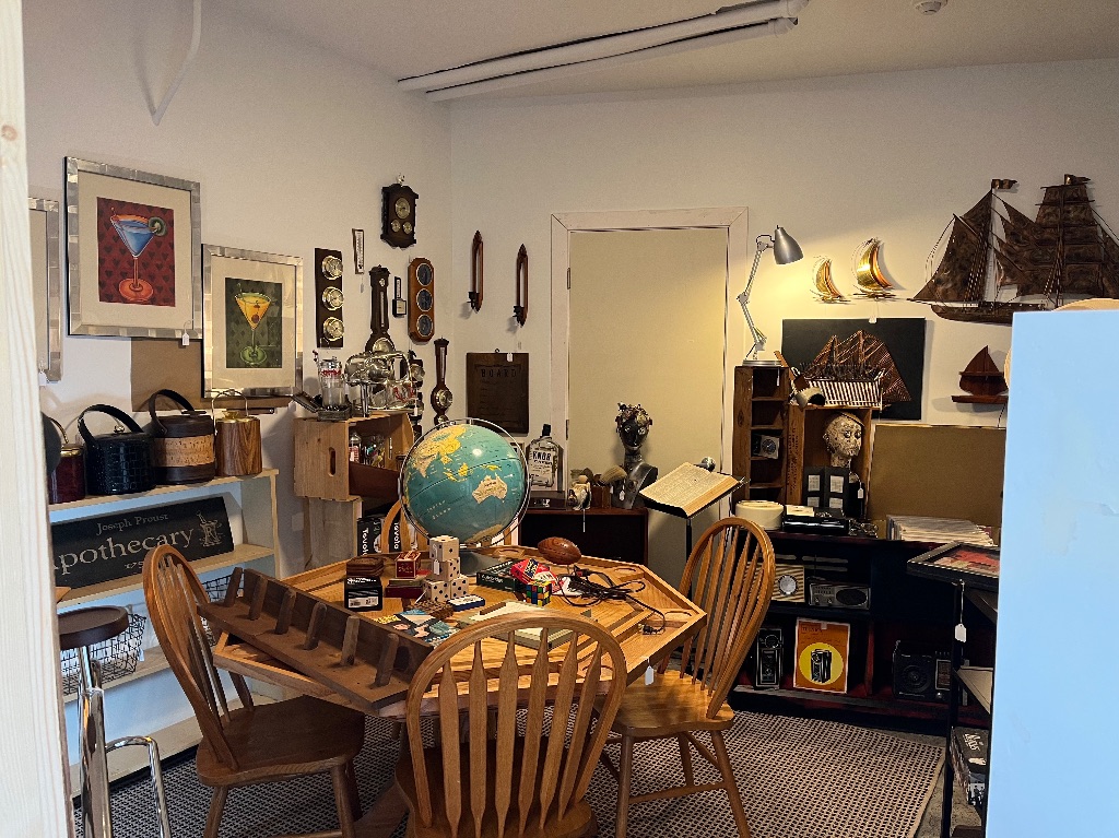The inside of the Digs store. There is a table and chairs in the middle of a small room. The room is full of other vintage wares on the walls and surrounding the table. 