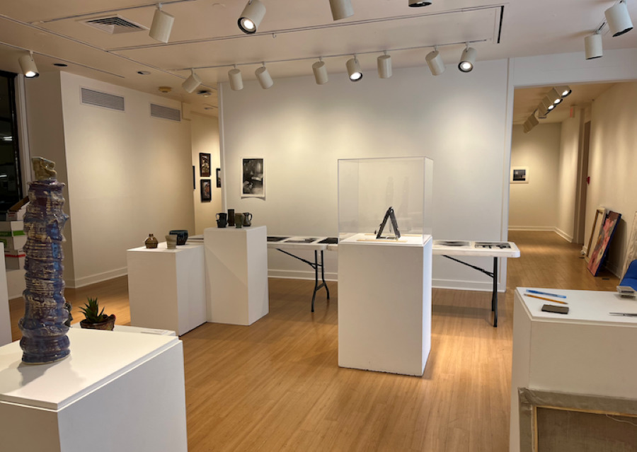 An art gallery with white walls and white pedestals throughout, display art pieces.