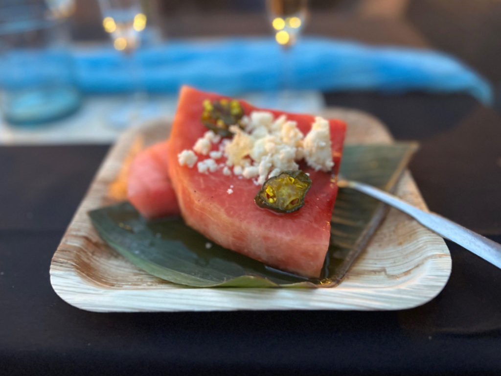 On a brown square plate, there are two slices of watermelon with queso fresca and candied jalapeños. Photo by Alyssa Buckley.