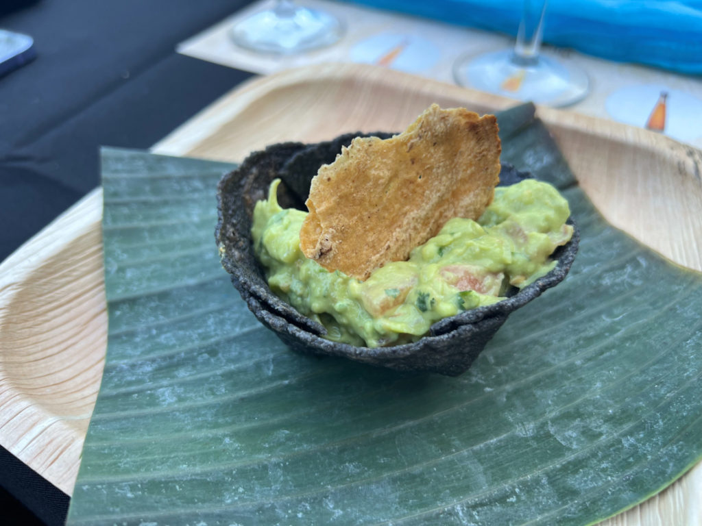 A blue corn tortilla chip boat holds guacamole with a broken chip sticking out of the top on a banana leaf-lined plate at Maize's tequila dinner. Photo by Alyssa Buckley.