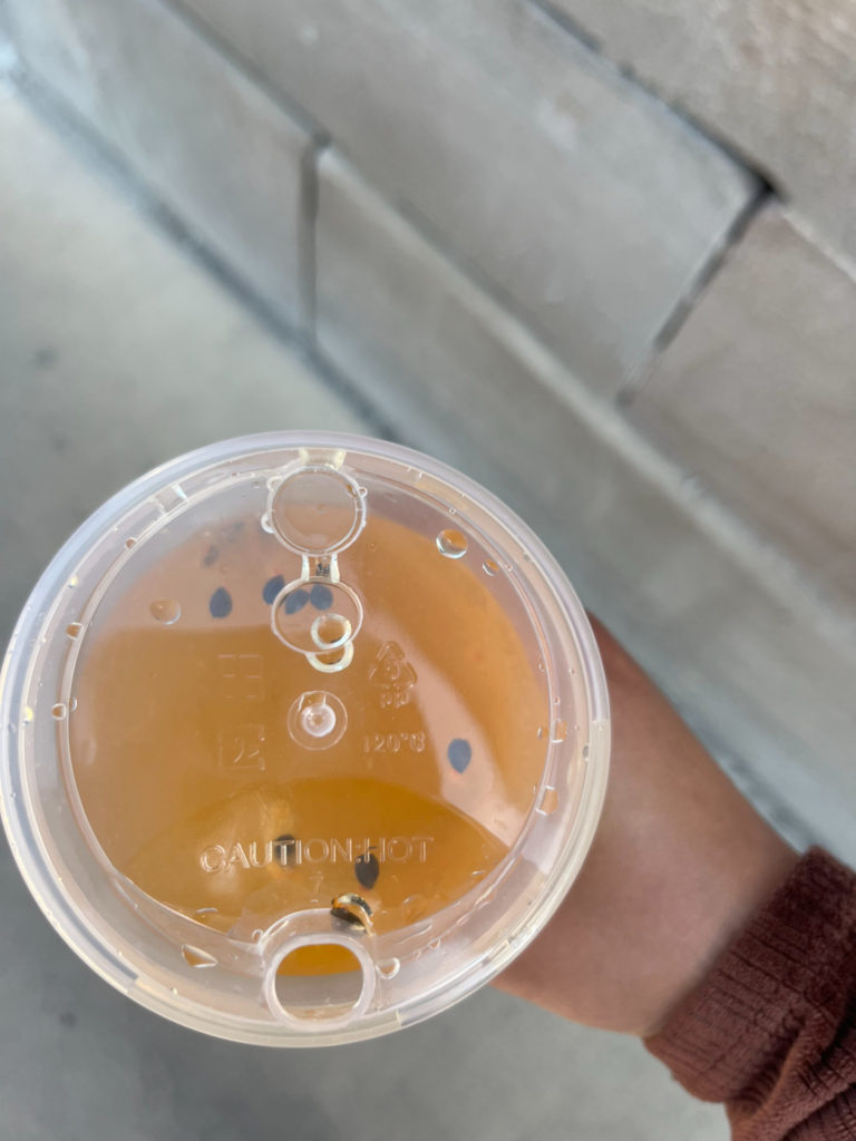 An overhead photo of a Teamoji orange cold drink in a plastic cup. Photo by Ayesha Mehta.