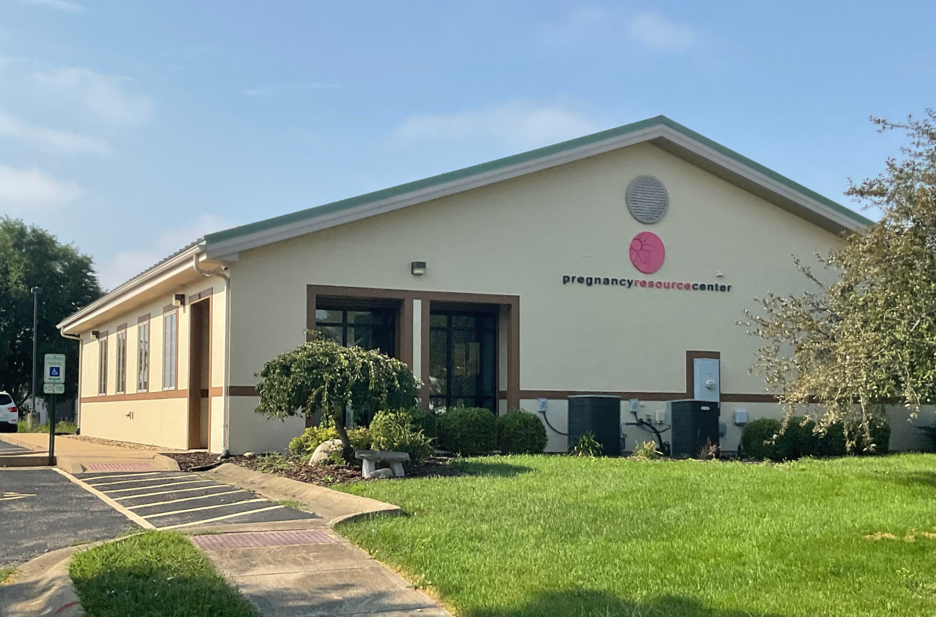 The Pregnancy Resource Center in Champaign is an anti-abortion clinic. A cream colored building with brown trim. There is a pink logo on the side of the building with the words pregnancy resource center underneath.