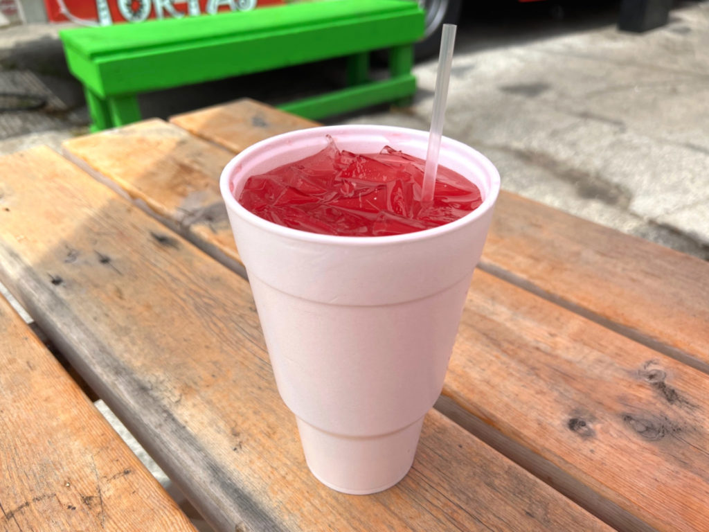 A watermelon water is in a large white styrofoam cup with ice and a disposable plastic straw. Photo by Alyssa Buckley.