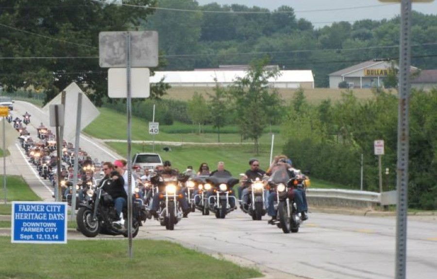 A long line of motorcycle riders are traveling along a road.