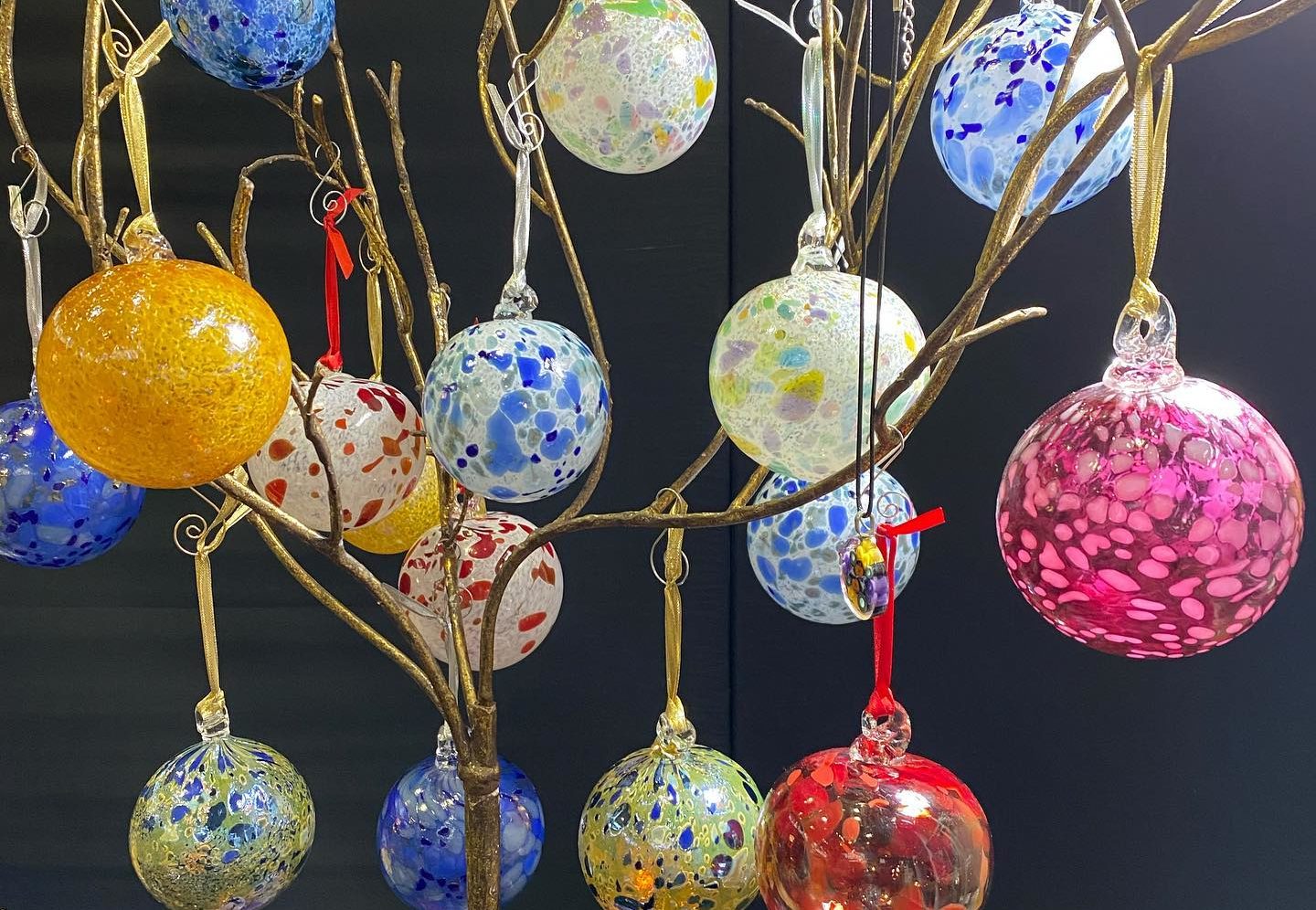 Blown glass ornaments hang on a display tree