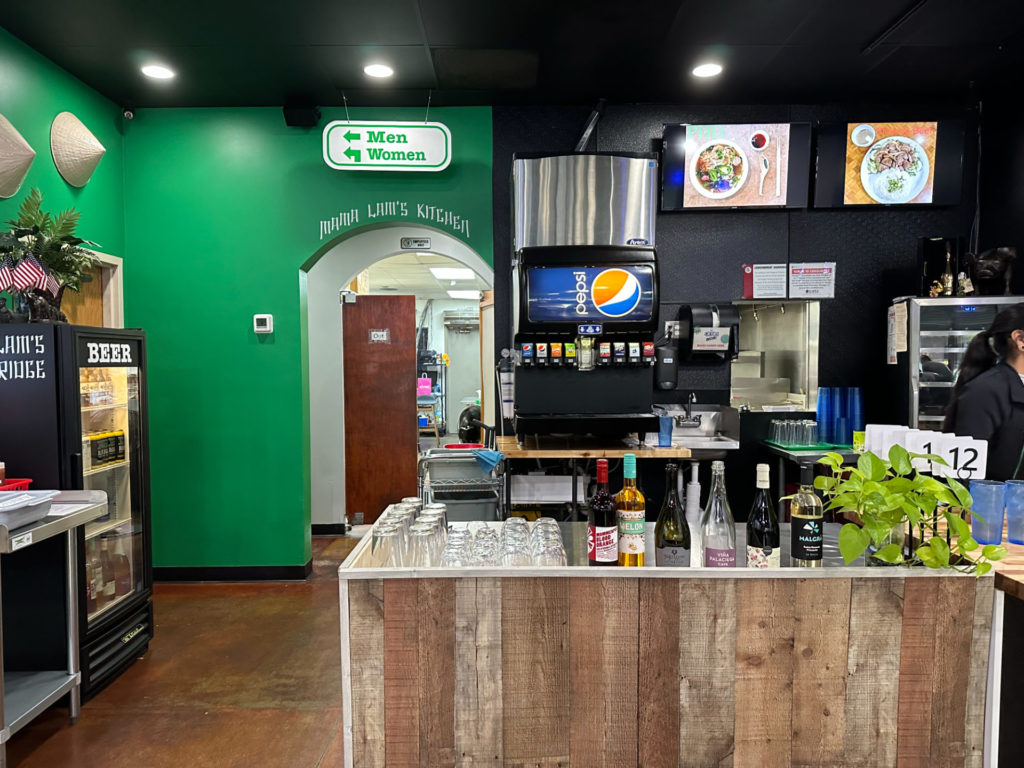 Inside 83 Vietnamese, there is a green wall with hand-painted lettering in white reading "Mama Lam's Kitchen."